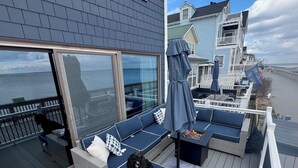A deck with a sofa, a fire pit, and a dog. - 3 bedroom, waterfront cottage on the shores of the Chesapeake Bay. (North Beach)