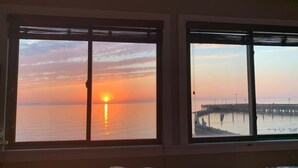 A room with two windows overlooking a sunset over water and a pier. - 3 bedroom, waterfront cottage on the shores of the Chesapeake Bay. (North Beach)
