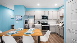 A modern kitchen with white cabinets, stainless steel appliances, and a wooden dining table set for four. - Cozy 3BR/2.5BA Retreat in Nashville/Old Hickory, 20min to Downtown & Airport (Nashville)