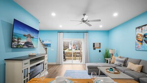 A modern living room with a wooden dining table, grey sofa, and a view of the outdoors through a glass door. - Cozy 3BR/2.5BA Retreat in Nashville/Old Hickory, 20min to Downtown & Airport (Nashville)
