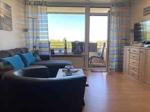 A living room with a sofa, a television, and a view of the outdoors through a sliding glass door.
