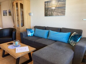 A modern living room with a grey sectional sofa, a wooden coffee table, and a glass cabinet.