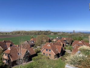 A residential area with houses having red-tiled roofs, surrounded by green fields and a clear blue sky. - Berolina 408 - Sonnenplätzchen - "Sonnenplätzchen" dreamlike sunsets (Dahme)