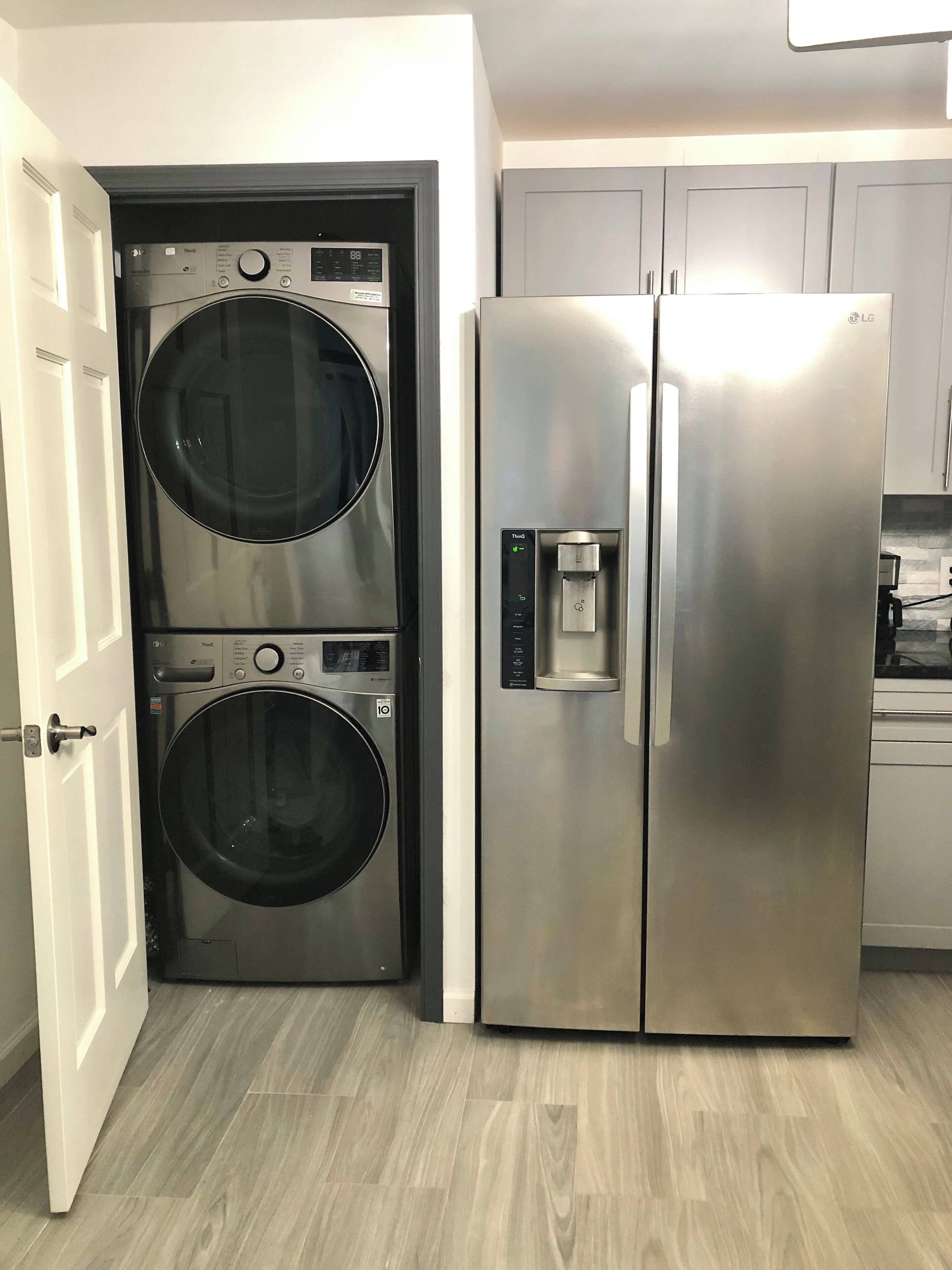 Une cuisine compacte équipée d’un réfrigérateur en acier inoxydable et d’un appareil combiné lave-linge et sèche-linge à deux portes.