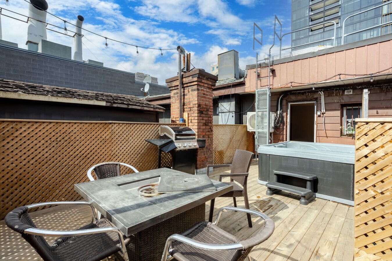 Un patio al aire libre con una parrilla, zona de estar y un jacuzzi.