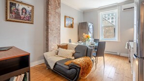 Ein modernes Wohnzimmer mit Sofa, Esstisch und Küchenzeile.