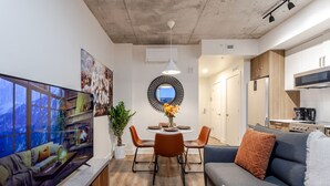 Un espace de vie compact comprenant un téléviseur, un coin repas, un canapé et une kitchenette.