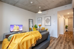 Una sala moderna con sofá, televisor y comedor.