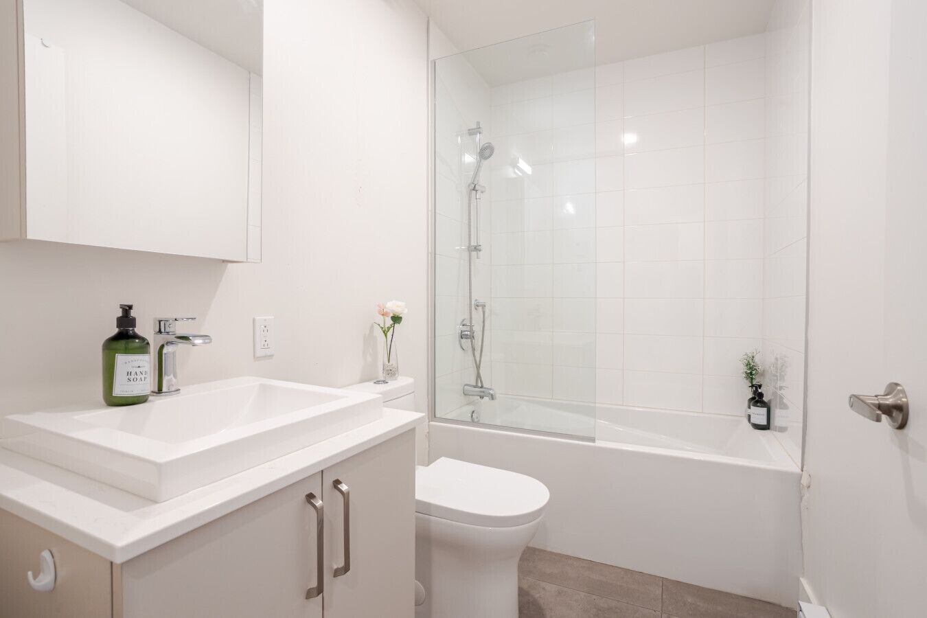 Une salle de bain moderne avec un lavabo blanc, des toilettes et une douche à parois de verre.