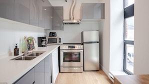 A modern kitchen with stainless steel appliances, a window, and a view of the street.