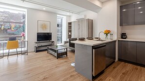 Una cocina moderna con una isla central, electrodomésticos integrados y un comedor con televisor y asientos.