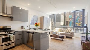 Una cocina moderna con una isla central, electrodomésticos de acero inoxidable y una zona de comedor con sofá y mesa de centro.