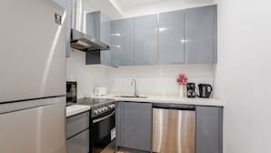 Una cocina compacta con armarios grises, lavavajillas de acero inoxidable, horno empotrado y microondas.