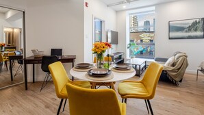 Un espace repas moderne avec des chaises jaunes, une table ronde et un vase de fleurs.