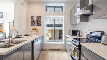 A modern kitchen with a central island, stainless steel appliances, and a large window.
