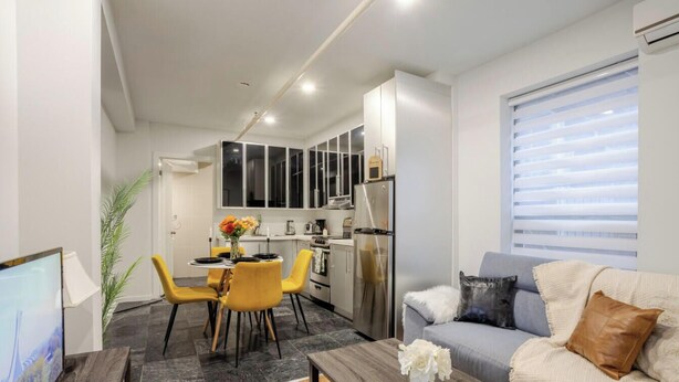 A compact living space with a dining area, kitchenette, and a sofa with a window view. - Charming 1BDR – Prime Location on Bishop St (Montréal)