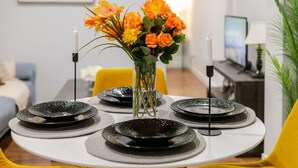 A dining table set with black plates and a vase of orange flowers. - Charming 1BDR – Prime Location on Bishop St (Montréal)