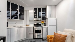 A compact kitchen with white cabinets, a built-in oven, and a refrigerator.