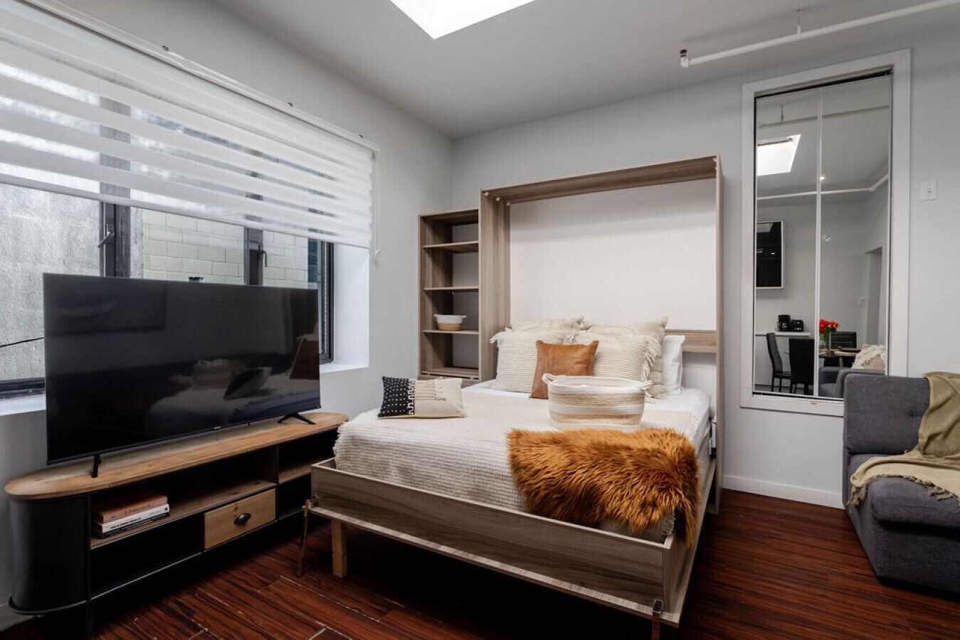 Un dormitorio moderno con una cama grande, un televisor y un armario.