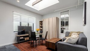Ein modernes Wohnzimmer mit Flachbildfernseher, Esstisch aus Holz und grauem Sofa.