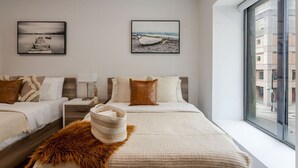 A modern hotel room with two beds, a large window with a city view, and artwork on the walls. - Vibrant MTL Living – 1BDR in a Top Location (Montréal)