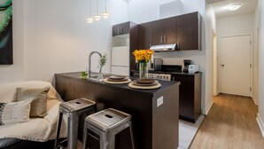 Una cocina moderna con armarios oscuros, una isla central y una zona de comedor con taburetes.
