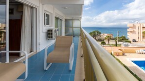 A balcony with a blue tiled floor, a pool, and a view of the sea.