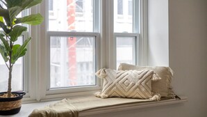 A window seat with a plant, pillows, and a throw blanket.