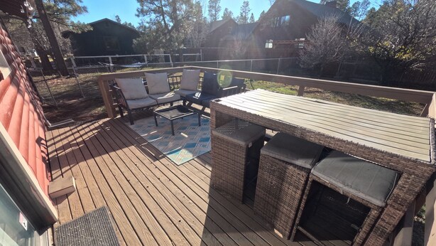A wooden deck with outdoor furniture, including a sofa and chairs, and a small table.
