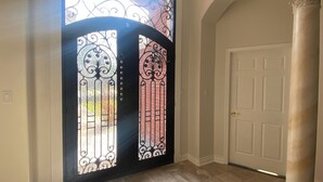 A hallway with a double door featuring ornate metalwork and a view through the glass panels. - 8BR Home • Near IAH & Downtown • Sleeps 17 • Spacious & Private backyard for BBQ (Humble)
