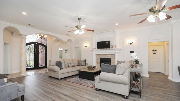 A spacious living room with a fireplace, two sofas, a coffee table, and a TV. - 8BR Home • Near IAH & Downtown • Sleeps 17 • Spacious & Private backyard for BBQ (Humble)