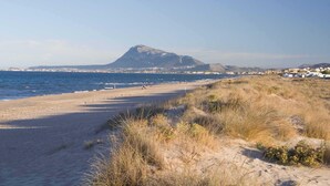 Una playa con una montaña al fondo y edificios a lo largo de la orilla.