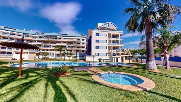 Un hotel con piscina, palmeras y un césped bien cuidado.
