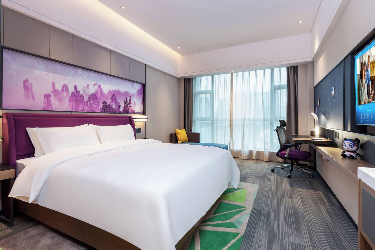 Une chambre d’hôtel moderne équipée d’un grand lit, d’un bureau, d’une chaise et d’un téléviseur.