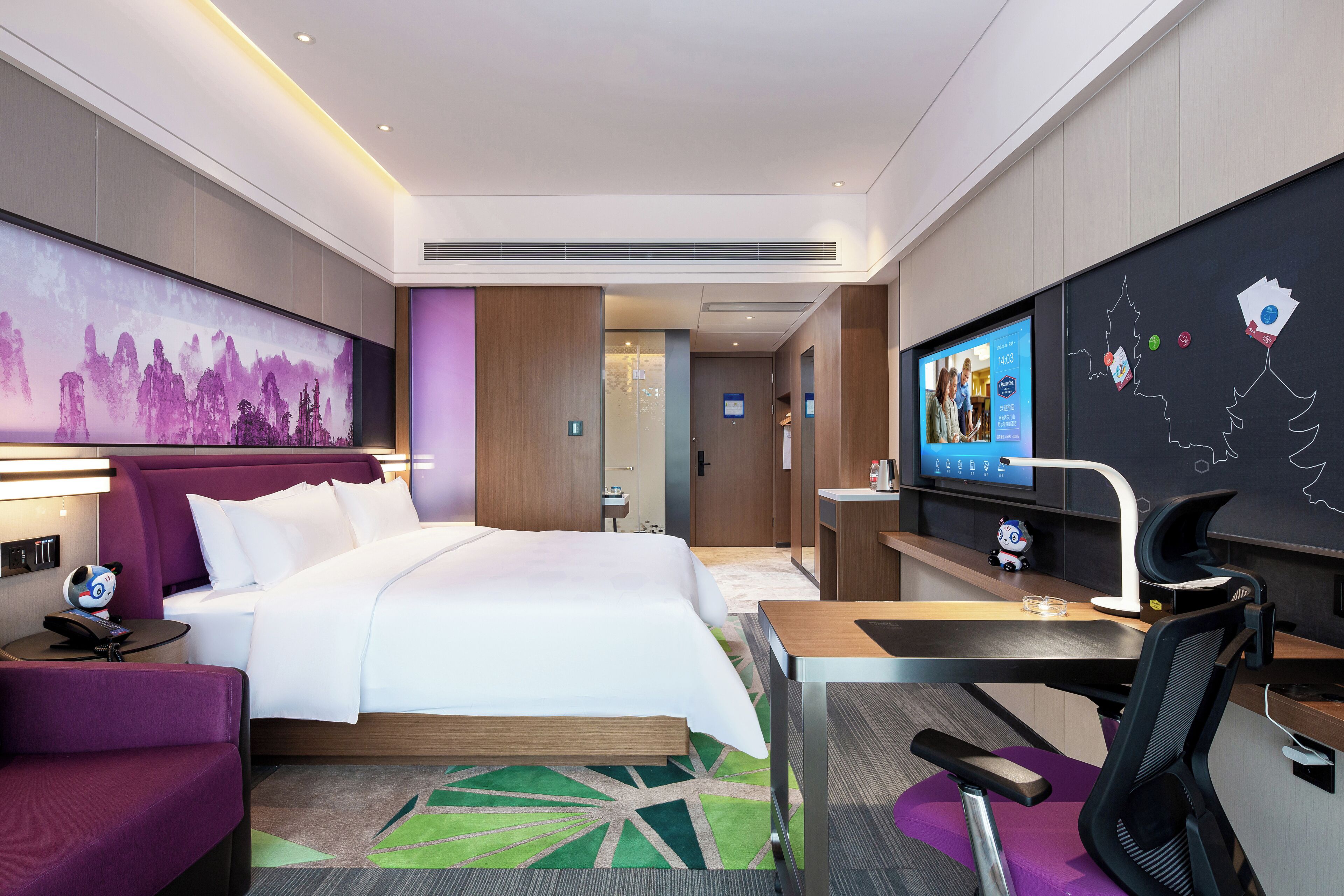 Ein modernes Hotelzimmer mit einem großen Bett, einem Schreibtisch mit Stuhl, einem Fernseher und einer großen Wandmalerei.