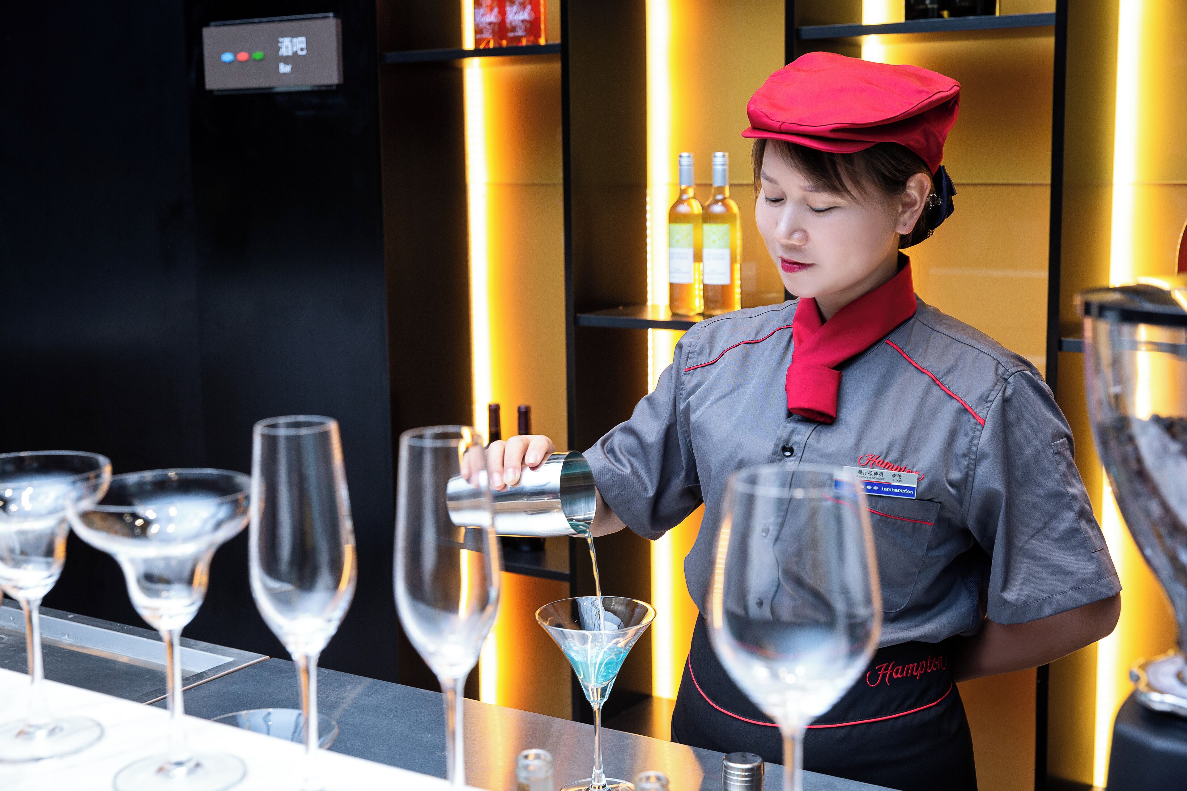 A bartender pouring a drink into a martini glass.