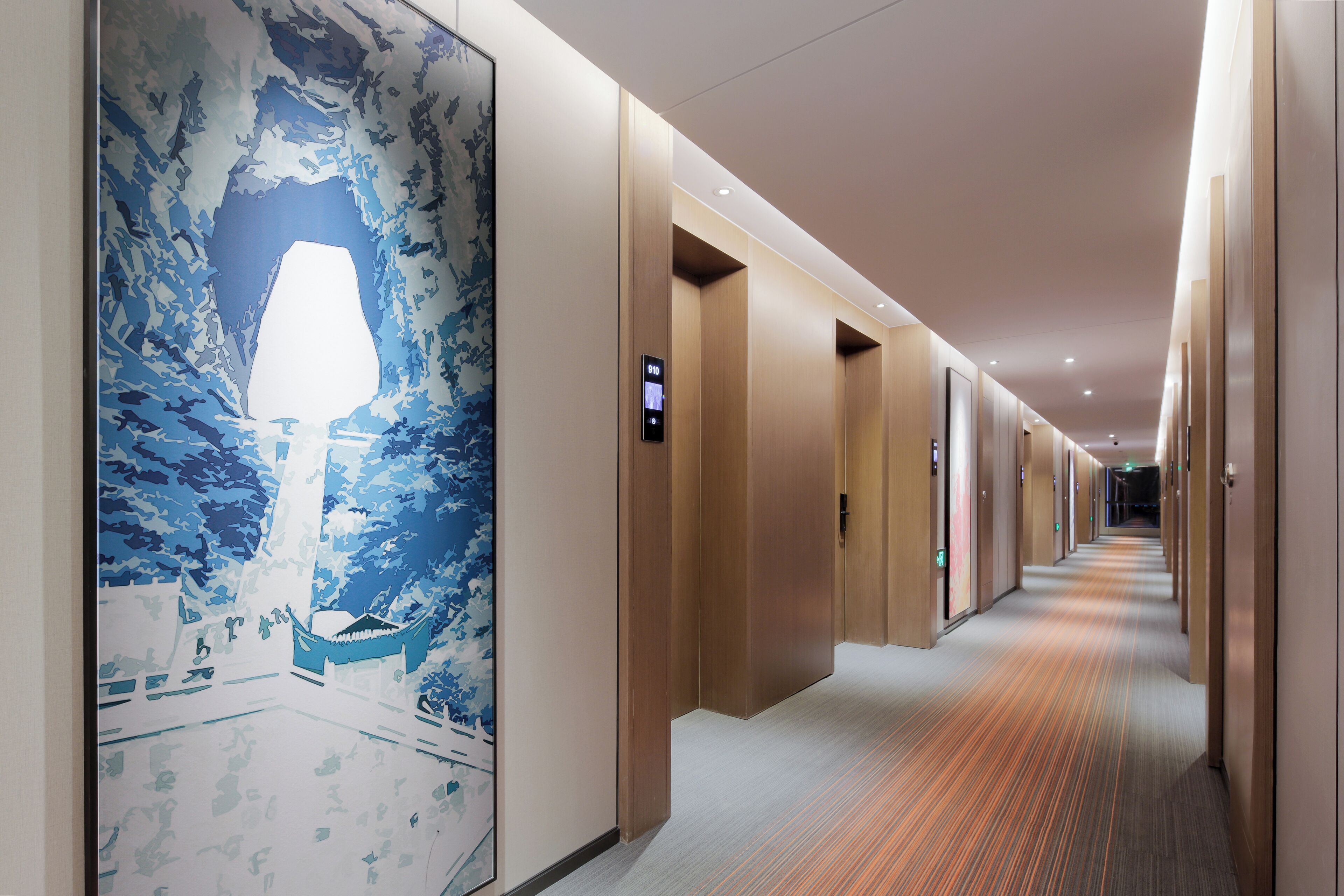 A hotel hallway with a patterned wall mural, wooden doors, and a carpeted floor.