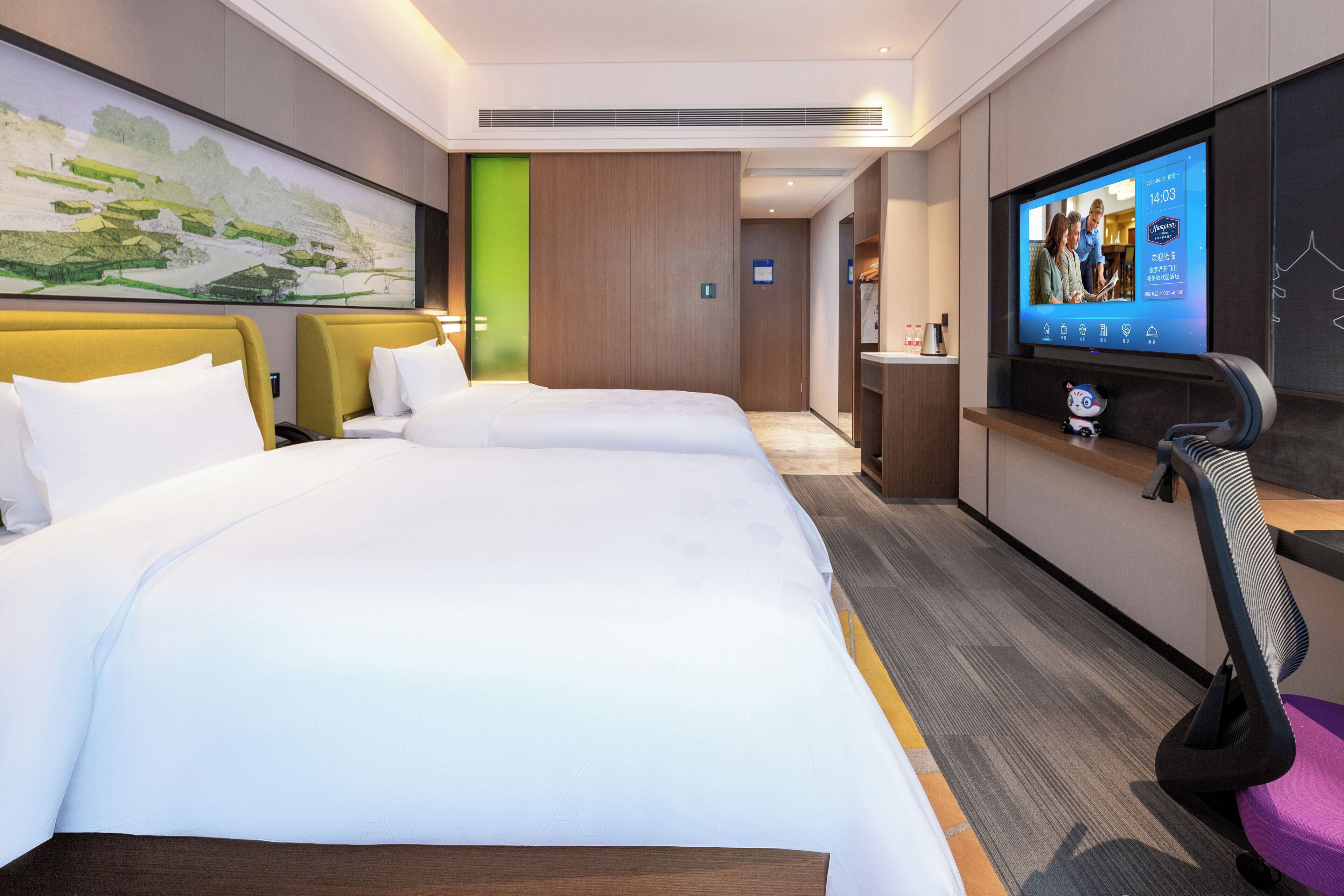 A hotel room with two beds, a TV, a desk, and a bathroom.