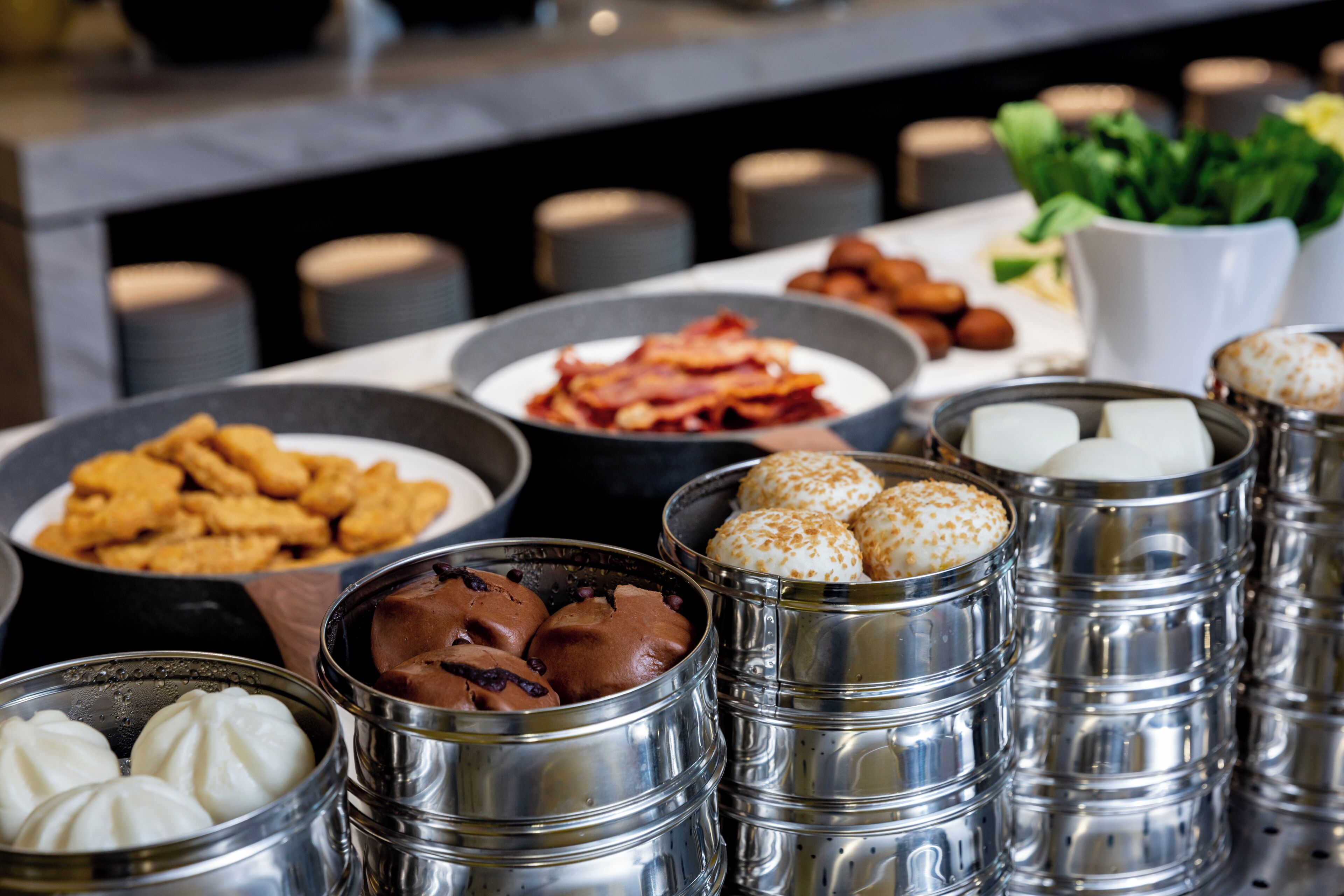 Un buffet proposant une variété d’aliments, notamment des pâtisseries, des biscuits et différents types de desserts, présentés dans des récipients en métal.