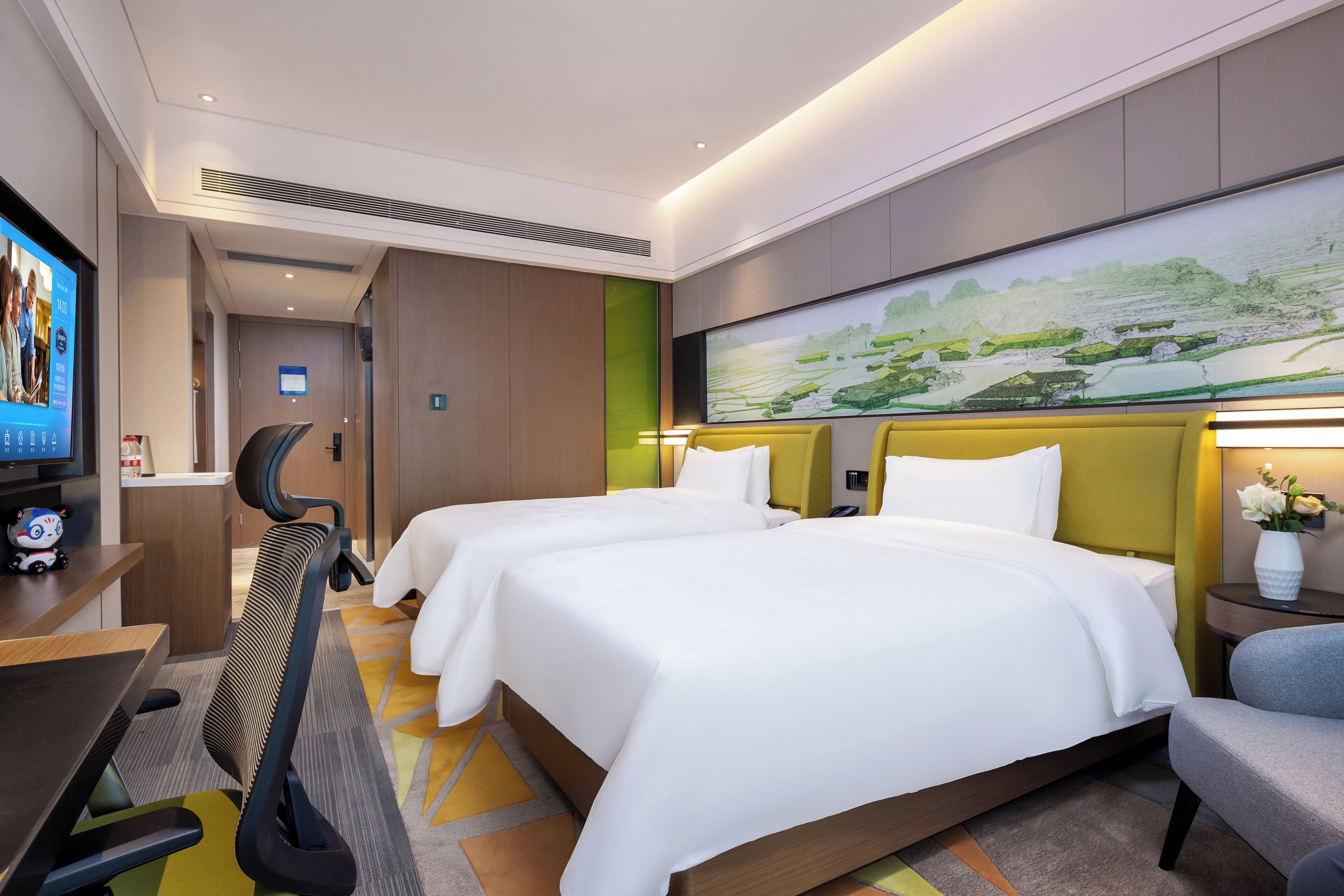 Habitación de hotel con dos camas, un escritorio con computadora, un televisor y un cuadro grande en la pared.