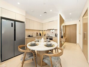 A modern kitchen with a built-in refrigerator, a dining table set for four, and a staircase leading to an upper level.
