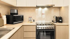 Una cocina moderna con estufa a gas, microondas y cafetera.