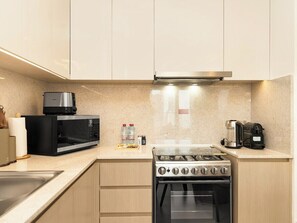 Una cucina moderna con piano cottura a gas, forno a microonde e macchina del caffè.