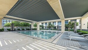 Una piscina interior moderna con zona techada, sillas de descanso y piso de baldosas.