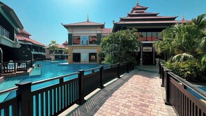 A hotel pool area with a traditional pagoda-style building, a clear sky, and a fenced walkway. - Anantara Sea & Burj Al Arab View / Private Beach (Dubai)