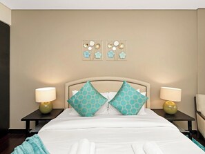 A hotel room with a bed, two nightstands, two lamps, and two wall art pieces.