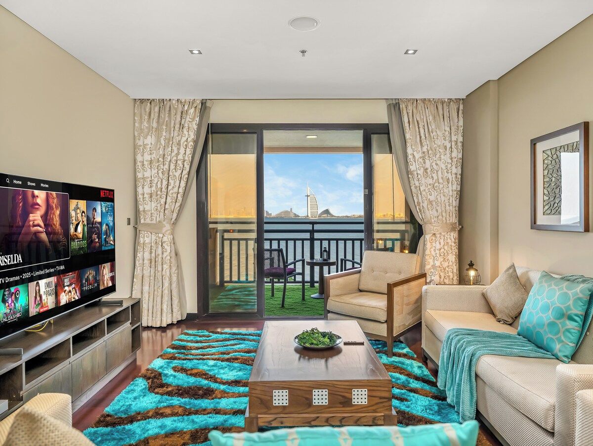 Ein Wohnzimmer mit Fernseher, Sofa, Couchtisch und einem Balkon mit Blick.