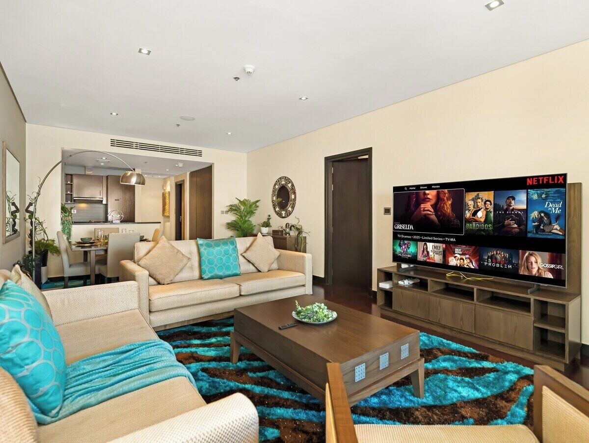 Een moderne woonkamer met een bank, salontafel en een flatscreen-tv waarop Netflix wordt afgespeeld.