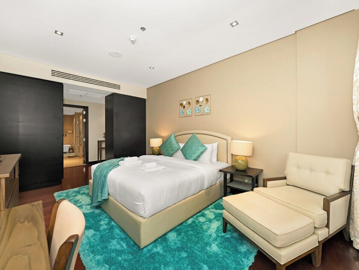 Een hotelkamer met een bed, een stoel, een bureau en een badkamer die door een open deur zichtbaar is.