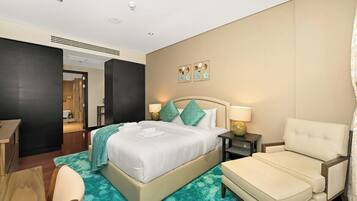 Een hotelkamer met een bed, een stoel, een bureau en een badkamer die door een open deur zichtbaar is.